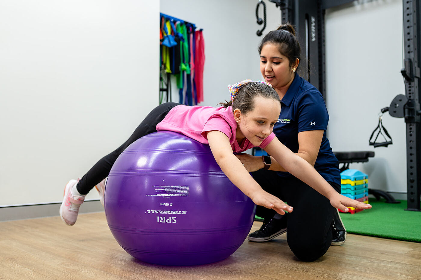 Child balancing on a swiss ball with a physiotherapist