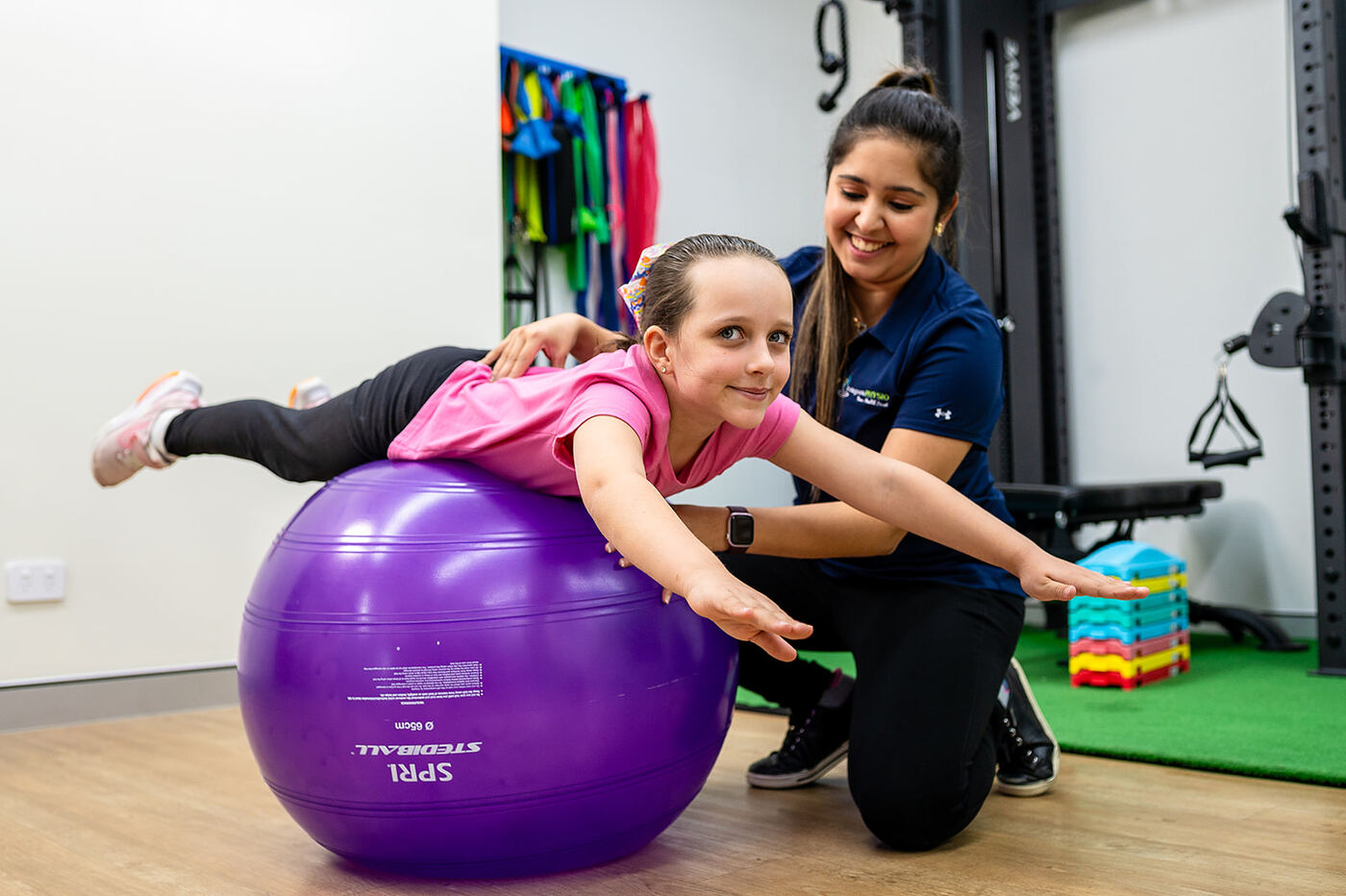 Child doing a swiss-ball balance exercise with a physiotherapist